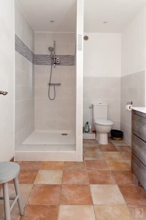 Une salle de bain moderne équipée d’une douche, de toilettes et d’un petit tabouret.