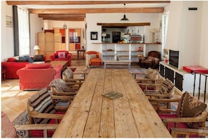 A spacious living room with a wooden dining table, red sofas, and a fireplace.