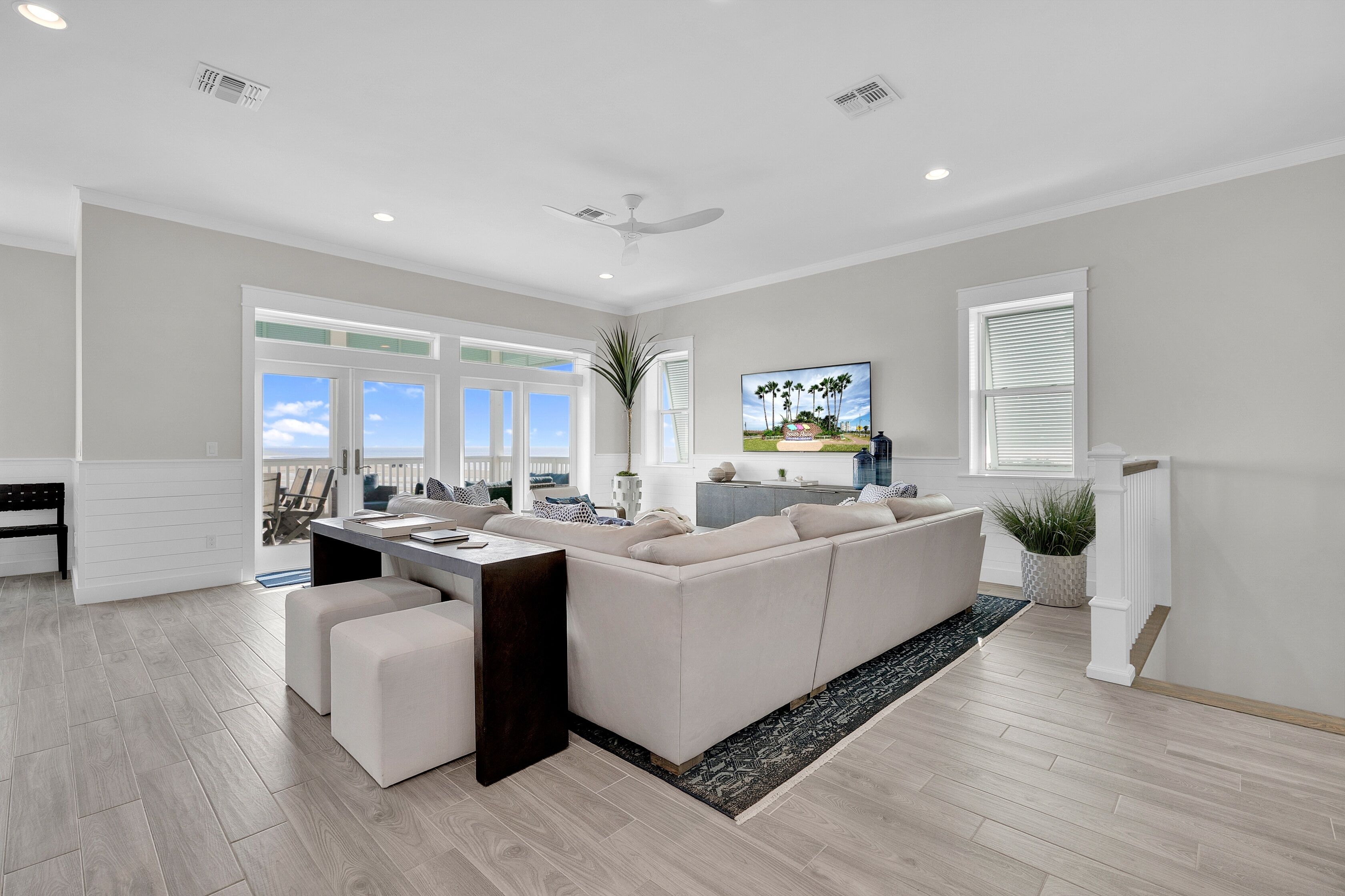 A modern living room with a large sectional sofa, a dining area, and a view of the outdoors.