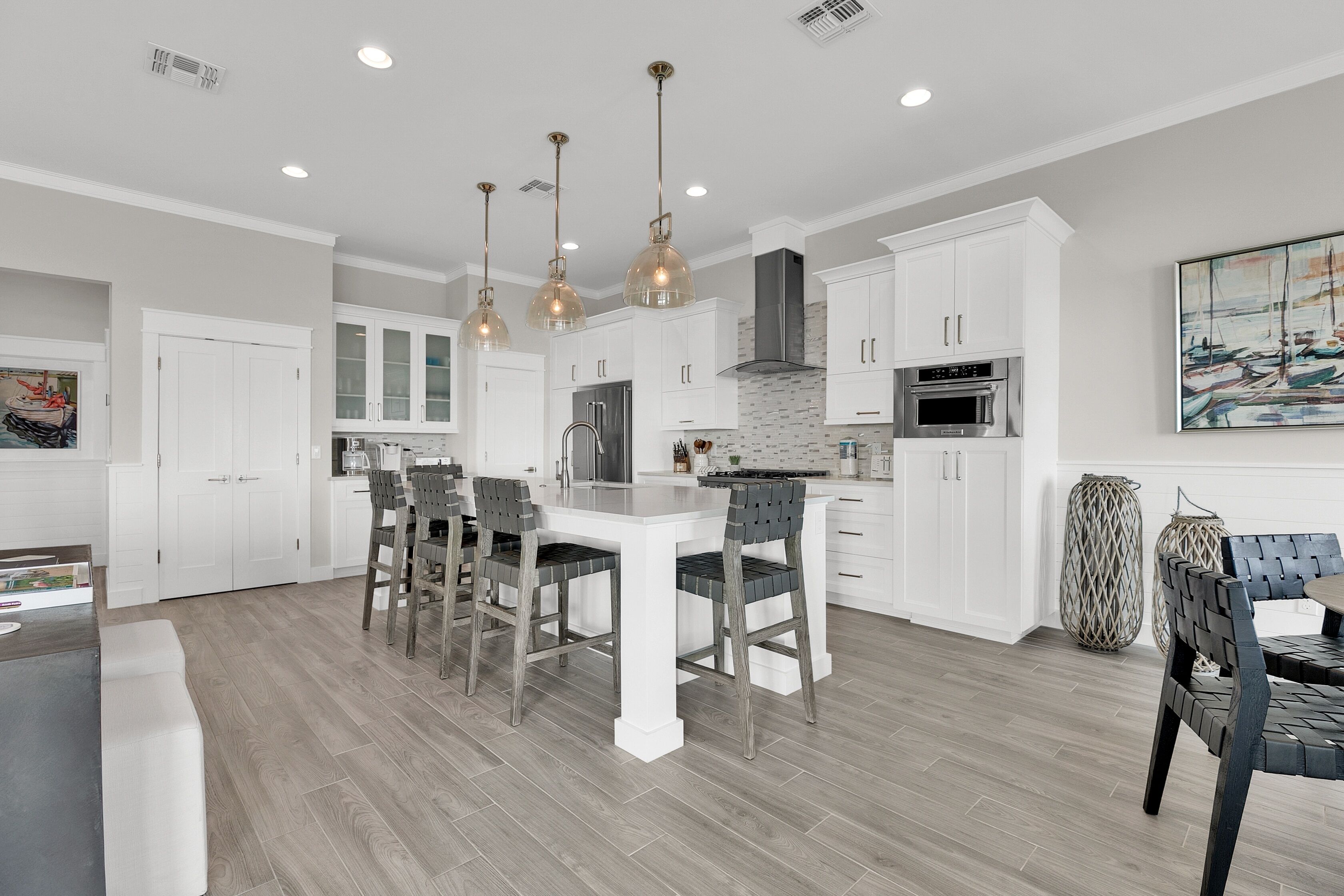 A modern kitchen with white cabinets, a central island, and pendant lighting.