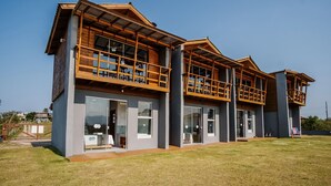 A modern two-story house with a balcony on the upper floor, large windows, and a flat roof. - Bangalos Luz da Lagoa (Imbituba)