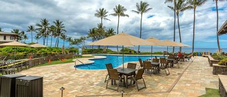A poolside area with a pool, lounge chairs, and umbrellas.