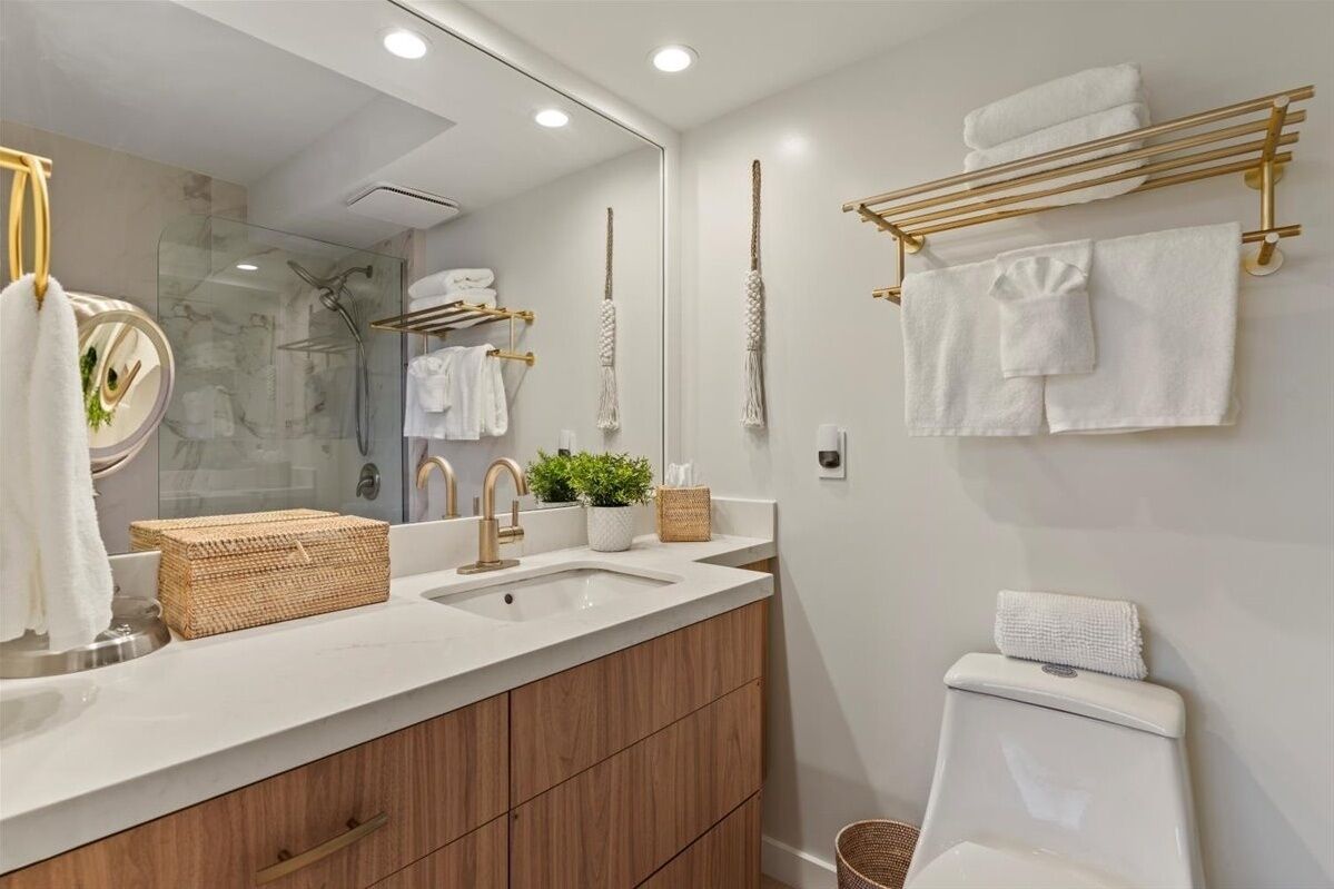 A modern bathroom with a large mirror, two sinks, a shower, and a towel rack.