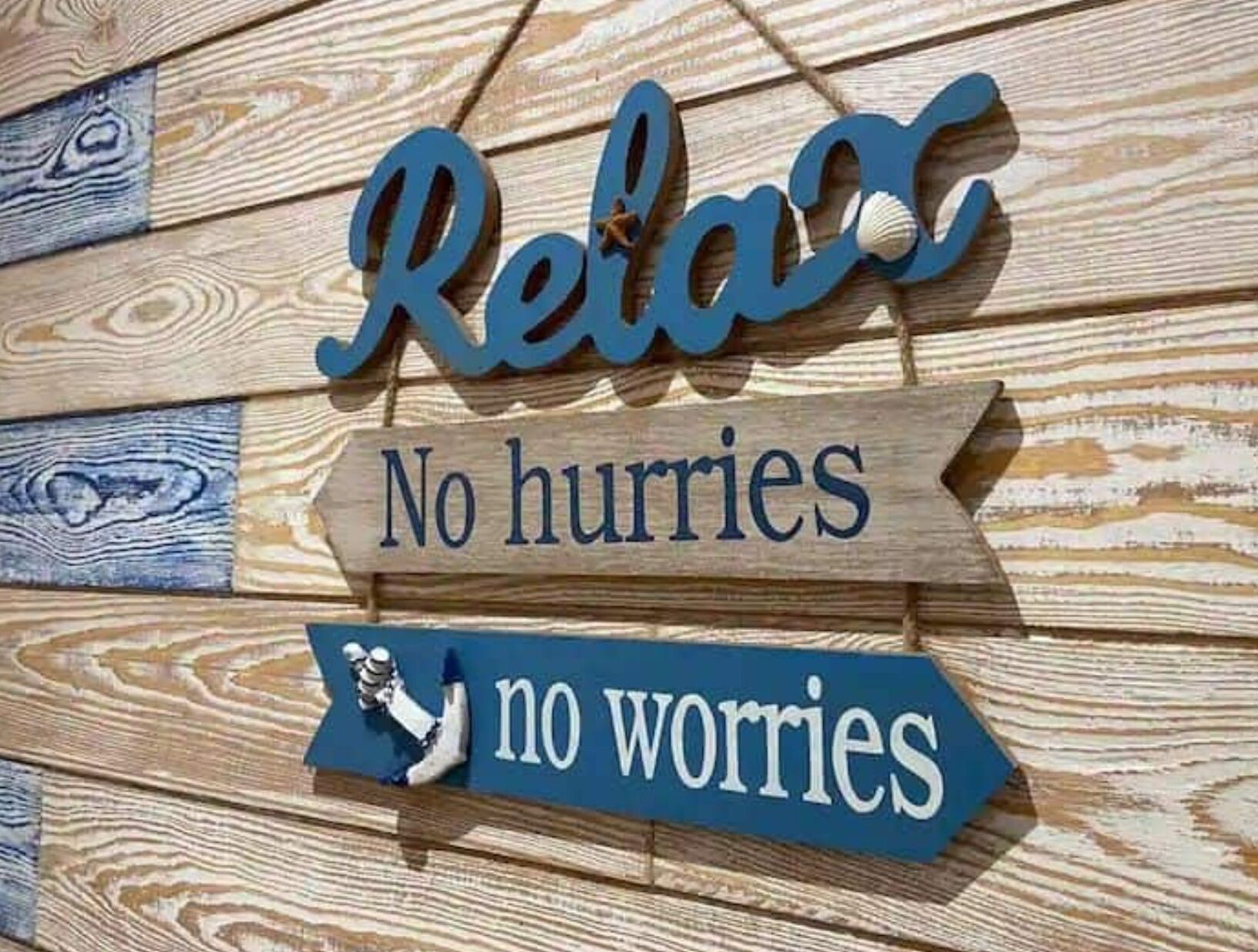 Una pared de madera con un letrero que dice 'Relax No hurries no worries'.