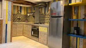 A kitchen with a stainless steel refrigerator, wooden cabinets, and a patterned backsplash. - Casa Caméléon (Essaouira)