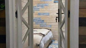 A narrow hallway with a bed at the end, wooden panel walls, and patterned floor tiles. - Casa Caméléon (Essaouira)