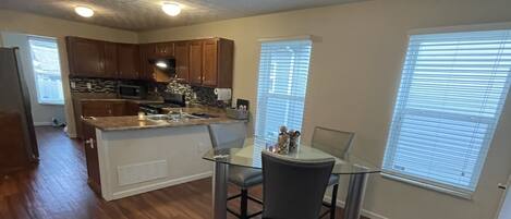 A spacious kitchen with wooden cabinets, a central island, and a dining area with a glass table and chairs.