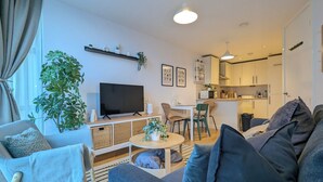 Ein modernes Wohnzimmer mit einer Couch, einem Fernseher und einem Essbereich.