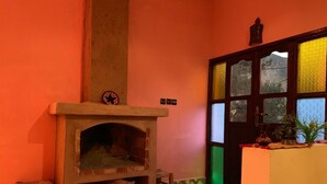 Une pièce avec un sol à carreaux, une cheminée, un petit tabouret et une porte à panneaux de verre.
