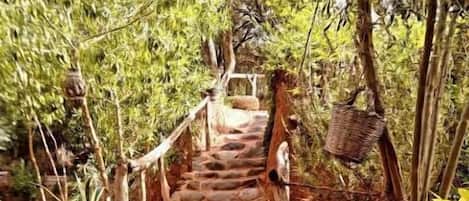 Una escalera de piedra que conduce a una terraza de madera rodeada de exuberante follaje y plantas en macetas.