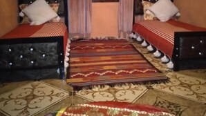 Une chambre avec deux lits, une grande moquette à motifs et une fenêtre avec des rideaux.
