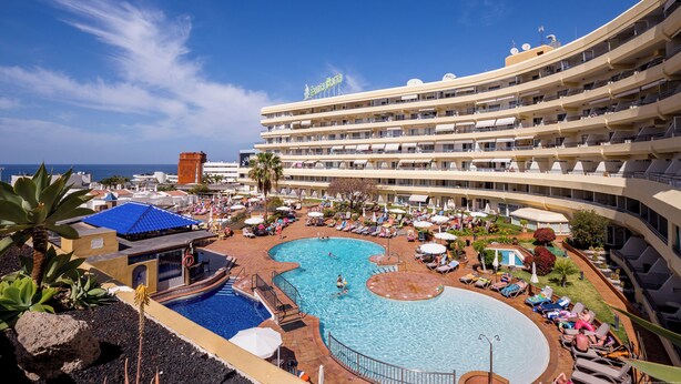 A resort with a large pool, multiple balconies, and a view of the ocean.