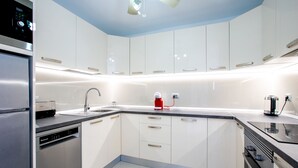 A modern kitchen with white cabinets, stainless steel appliances, and a black countertop.
