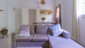 Una sala de estar moderna con un sofá gris, una mesa de comedor y un cuadro en la pared.