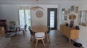 Uma sala de jantar com uma mesa redonda, cadeiras, um armário de madeira e uma porta com painel de vidro jateado.