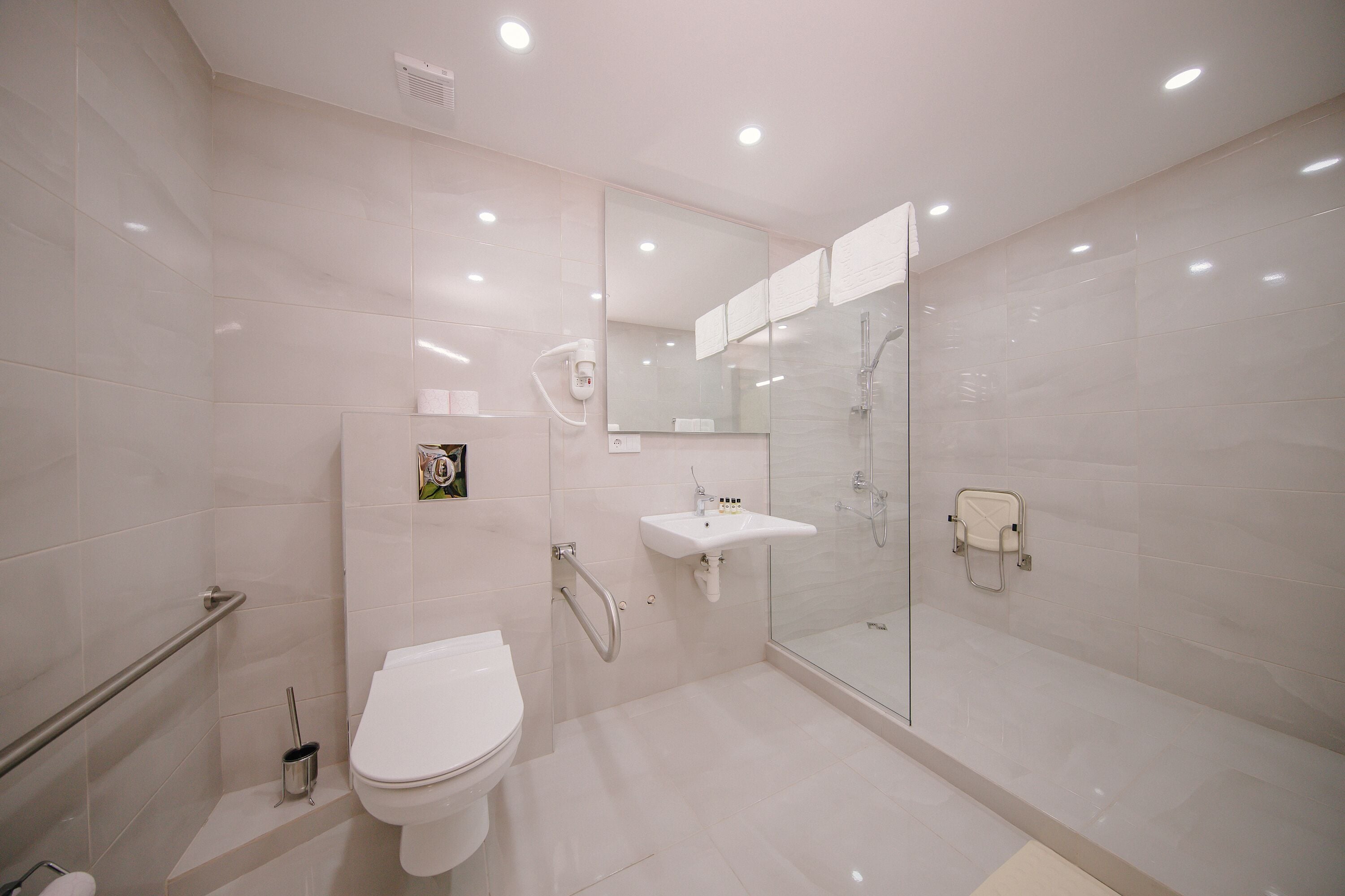 Une salle de bain moderne équipée de toilettes, d’un lavabo et d’une douche à parois de verre.
