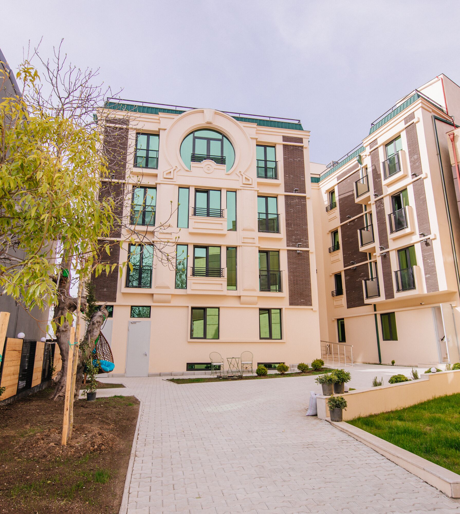 A multi-story residential building with a central courtyard, balconies, and a paved walkway.