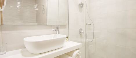 Une salle de bain moderne avec une douche à parois de verre, un lavabo blanc et un miroir au-dessus du lavabo.