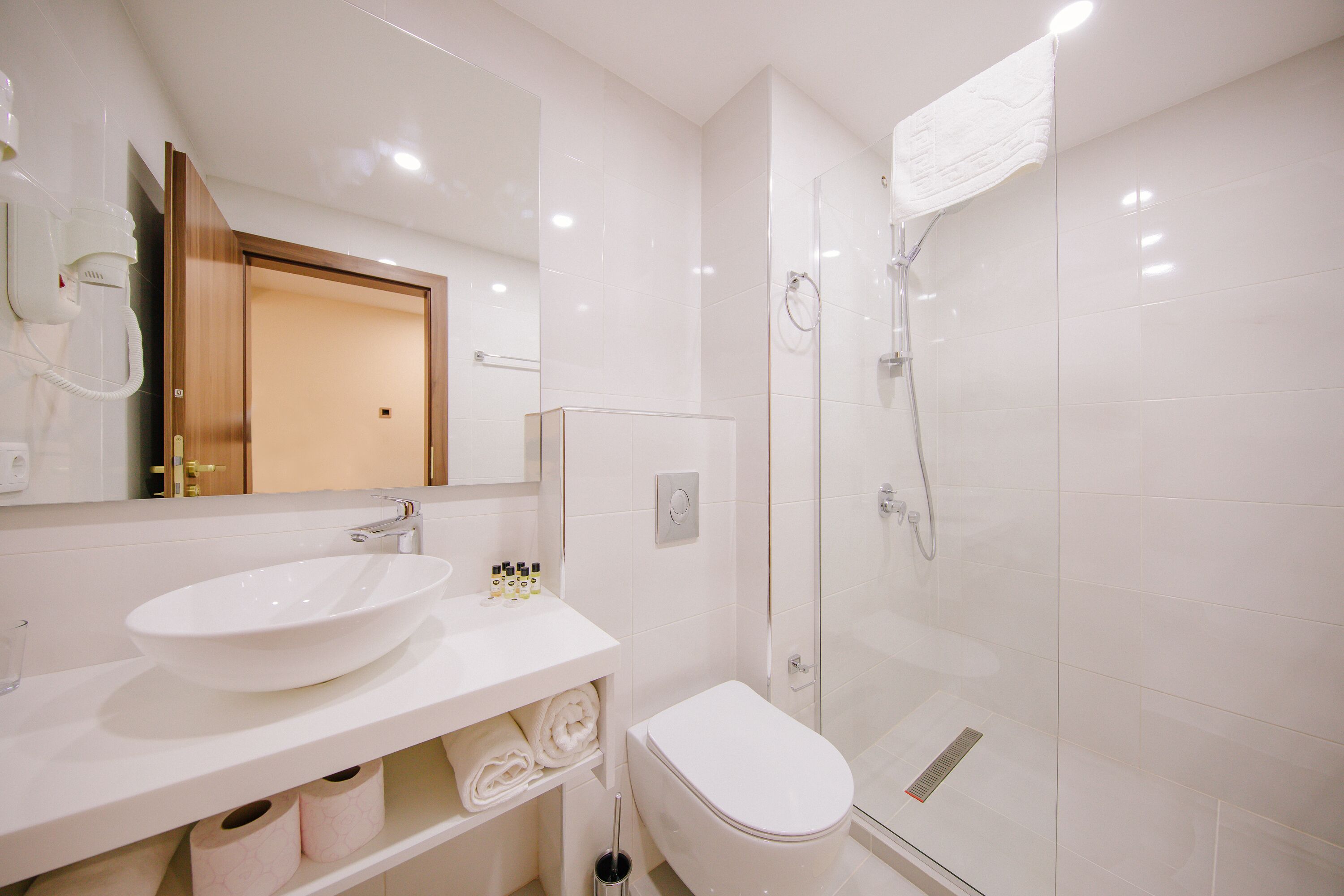 A modern bathroom with a white sink, toilet, and glass shower enclosure.