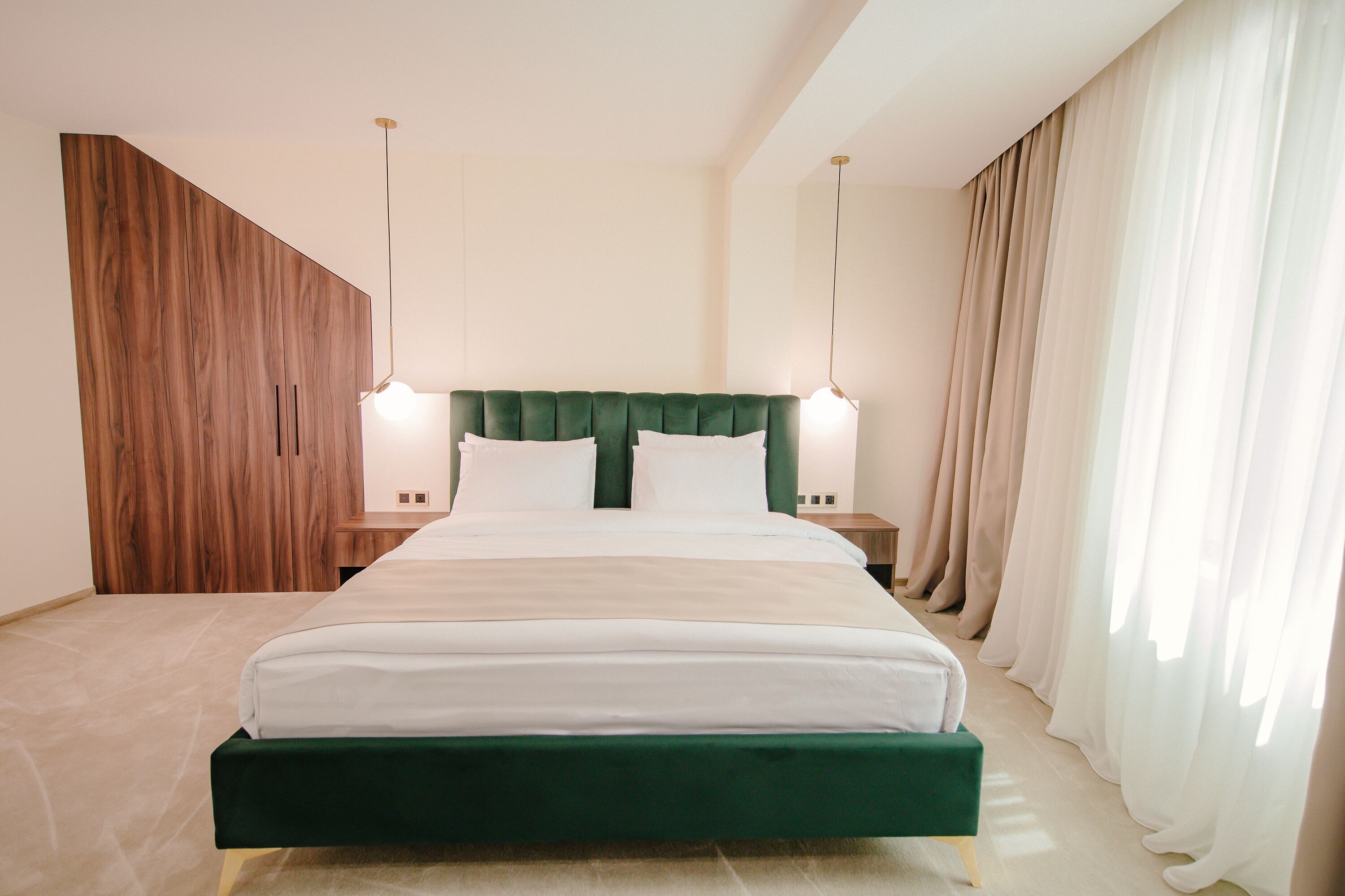 A modern hotel room with a large bed, wooden accent wall, and two bedside lamps.