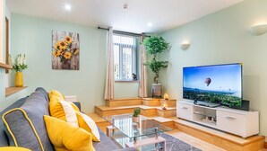 Een moderne woonkamer met een bank, televisie en sierplanten.