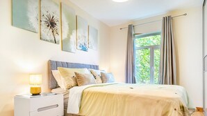 Een slaapkamer met een bed, nachtkastje en kunst aan de muur.