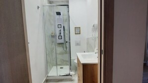 A modern bathroom with a glass shower enclosure, a wooden vanity, and a marble floor. - Via Salvatore Meccio (Palermo)