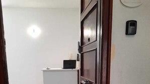 A room with a wooden door, a white desk, and a laptop. - Via Salvatore Meccio (Palermo)