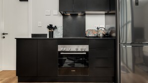 A modern kitchen with black cabinetry, a Bosch oven, and a stainless steel refrigerator. - Vibrant Central Studio at The Carrington (Cape Town)