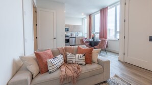 A modern living room with a beige sofa, a coffee table, and a dining area in the background.