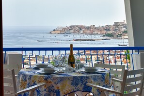 Une table dressée pour deux personnes, avec vue sur la mer et une ville côtière.