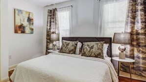 A bedroom with a bed, two bedside tables, a lamp, and a painting on the wall. - Luxury Historic Charm 1 mile to Forsyth Park (Savannah)