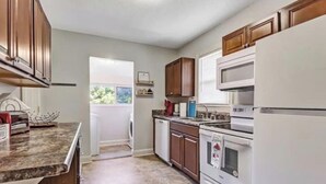 A kitchen with wooden cabinets, a white refrigerator, a microwave, and a stove. - Luxury Historic Charm 1 mile to Forsyth Park (Savannah)