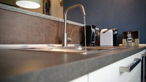 Una cocina moderna con un lavamanos de acero inoxidable, una cafetera y un juego de té.