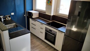 Una cocina moderna con armarios blancos, un refrigerador de acero inoxidable, horno integrado y una ventana sobre el fregadero.