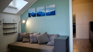 Una habitación acogedora con un sofá, un estante en la pared y un tragaluz.