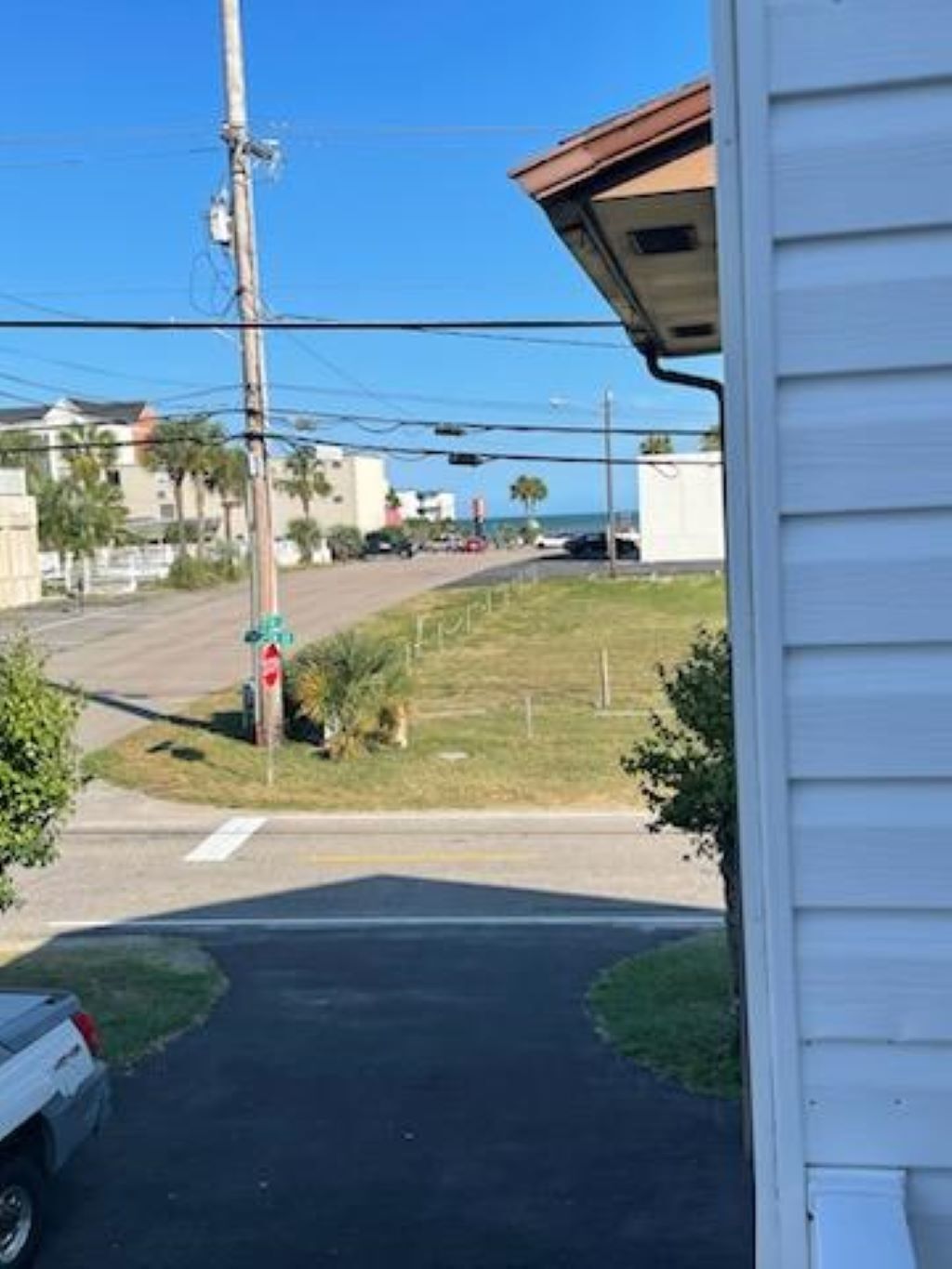 A residential street with a stop sign, a parked car, and houses in the background.