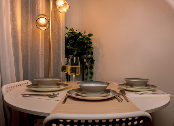 Enjoy a romantic dinner for two at this elegant dining area, complete with a round table, fine china, and a glass of wine.