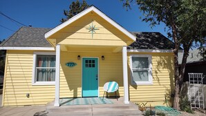 A yellow house with a turquoise door, a star decoration above the door, and a number '777' on the wall.
