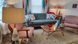 A living room with a sofa, armchairs, a coffee table, and a lamp.