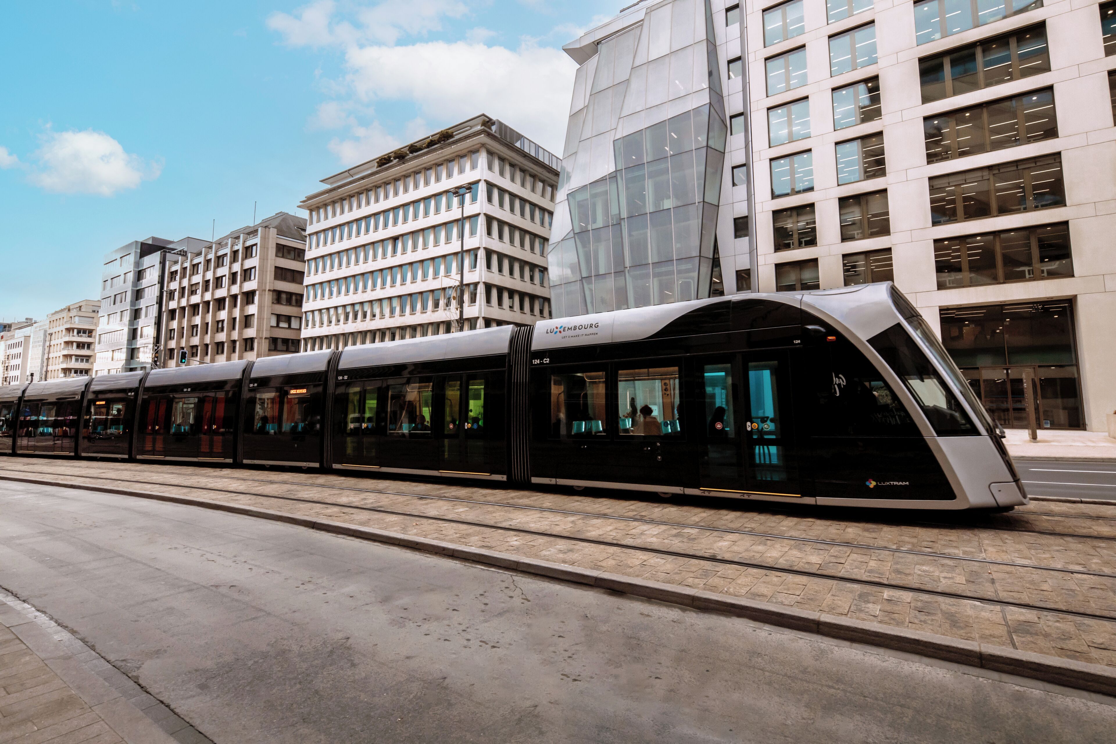 A modern train station with a sleek, curved train platform and contemporary buildings in the background.