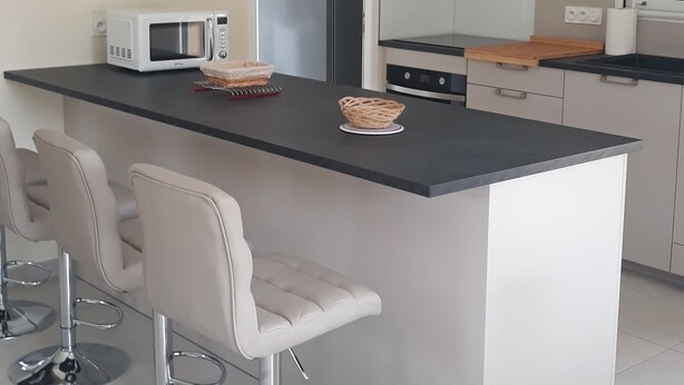 Una cucina moderna con isola centrale, sgabelli da bar, forno a microonde e frigorifero.