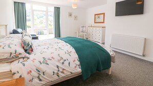 Een slaapkamer met een bed, een dressoir, een radiator en een televisie aan de muur.