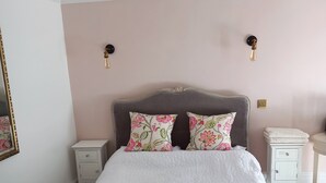 Une chambre à coucher comprenant un lit, deux tables de chevet, une commode et un miroir.