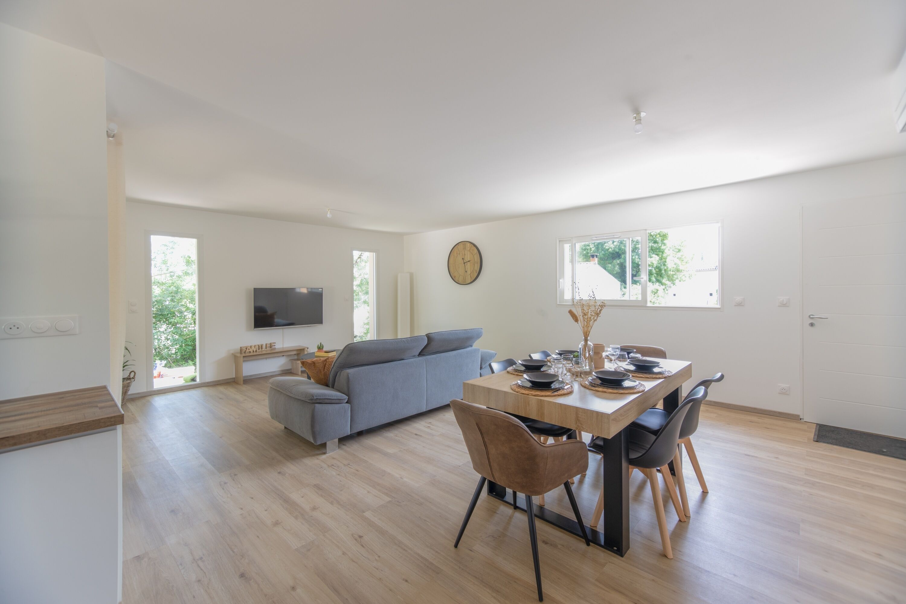 A spacious living area with a dining table, sofa, and TV.