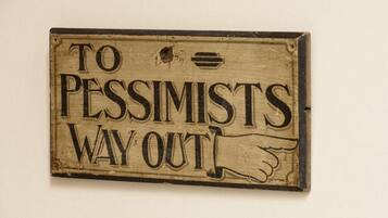A wooden sign with the text "TO PESSIMISTS WAY OUT!"