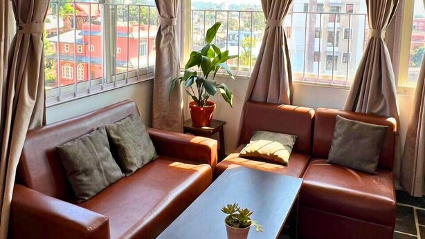 A room with two leather sofas, a small table, and a potted plant. - Deepjyoti Inn & Homestay (Kathmandu)