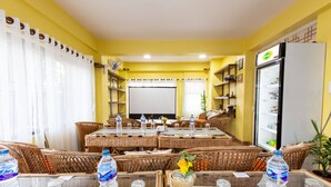A conference room with wicker furniture, a whiteboard, and a refrigerator stocked with beverages. - Deepjyoti Inn & Homestay (Kathmandu)