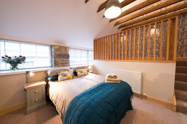 A bedroom with a bed, bedside table, lamp, window, and a bookshelf. - Beautiful 5 Bedroom Steading Conversion in Highland Perthshire (Aberfeldy)