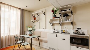 Une cuisine moderne avec des meubles blancs, un coin repas comprenant une table et des chaises, et un four encastré.